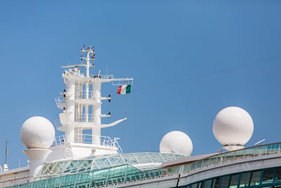 Satellite and Communication equipment on a cruise ship under blue skies and an Italian flag